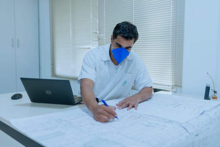 Engineer In His Office Working On Blueprints