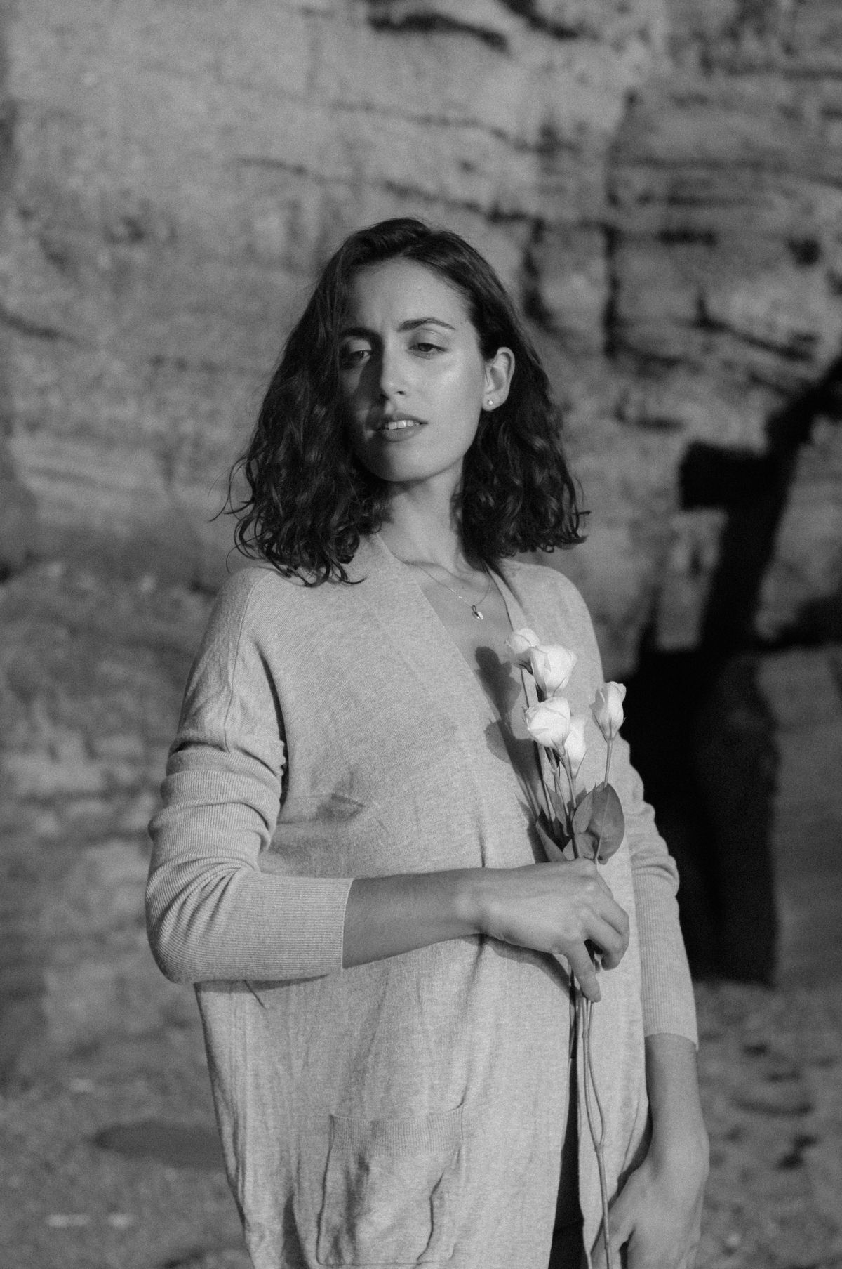 A black and white image of a woman in a fine knit cardigan holding flowers — the refined cardigan
