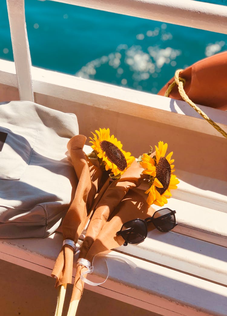 Canvas Bag, Sunflowers And Sunglasses On A Deck Of A Ship