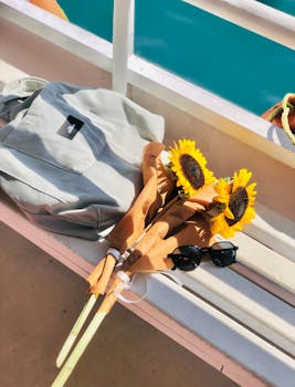 A casual arrangement of sunflowers, sunglasses, and a tote bag on a boat bench, capturing a sunny day.