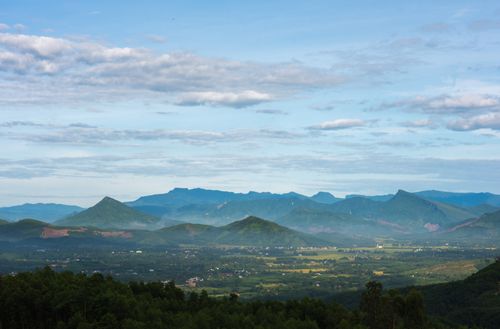 Free Expansive view of lush mountains and a peaceful countryside under a blue sky. Stock Photo