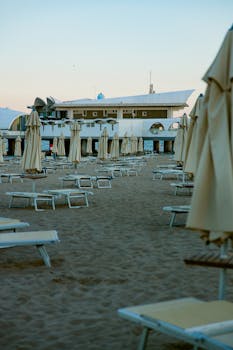 Empty sandy beach with lounge chairs and umbrellas at a luxury resort during sunset.