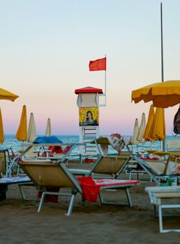 Serene beach scene featuring an empty lifeguard tower and loungers at sunset.
