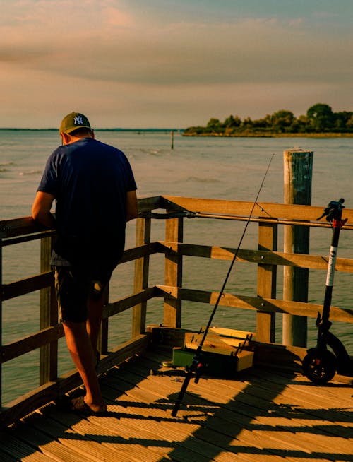 Back View of a Man Standing on a Wooden Dock