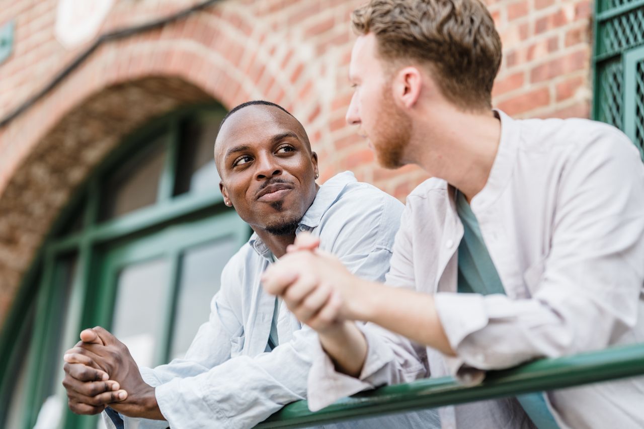 two men smiling and talking outdoors showcasing friendship and togethe