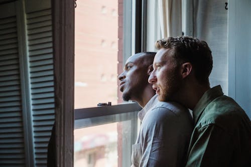 Gay Couple Hugging and Looking Out the Window 
