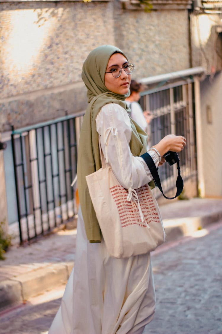 Woman In Beige Hijab Walking On Pavement