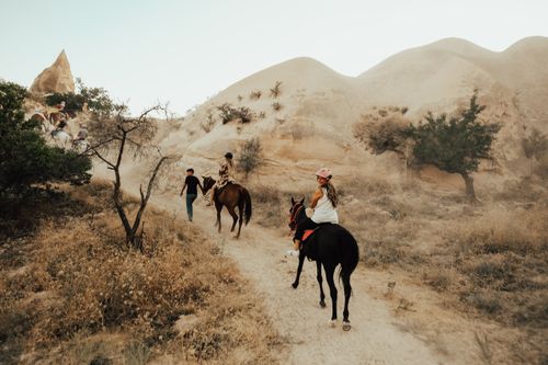 Free Women riding horses through sandy desert landscape, experiencing adventure. Stock Photo