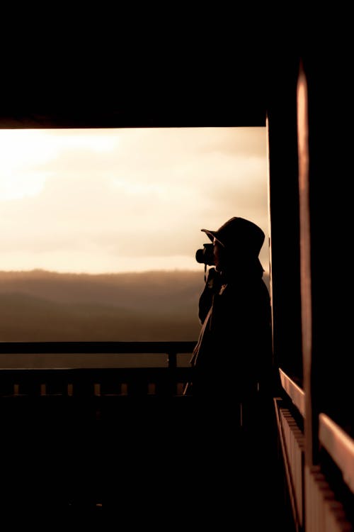 Silhouette of Photographer Taking Sunset Photos From Balcony