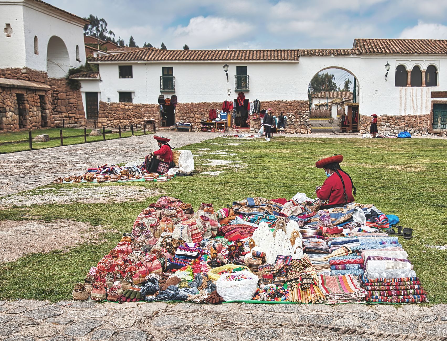 Best Things to Buy in Peru 2 Colorful Peruvian market scene with traditional textiles and crafts displayed in a historical outdoor setting.