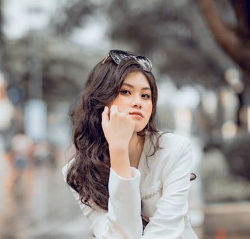 A fashionable young woman with sunglasses poses confidently outdoors.