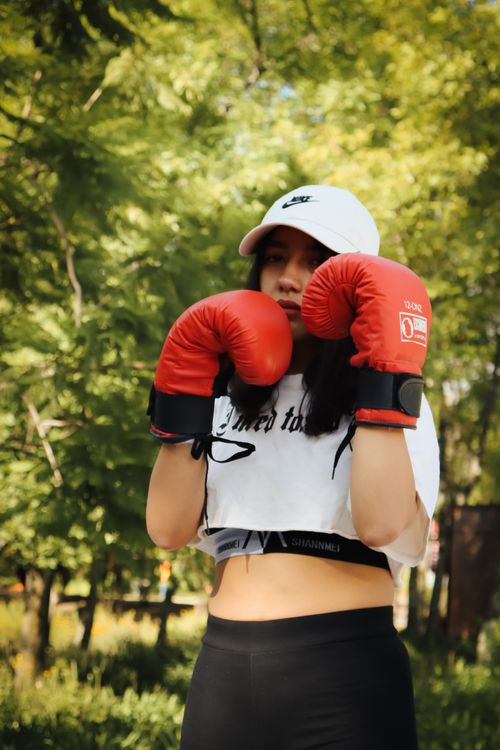 Free Confident young woman in boxing stance with gloves in Mexico City park. Stock Photo