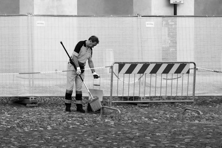 Grayscale Photo Of A Man Swiping The Floor