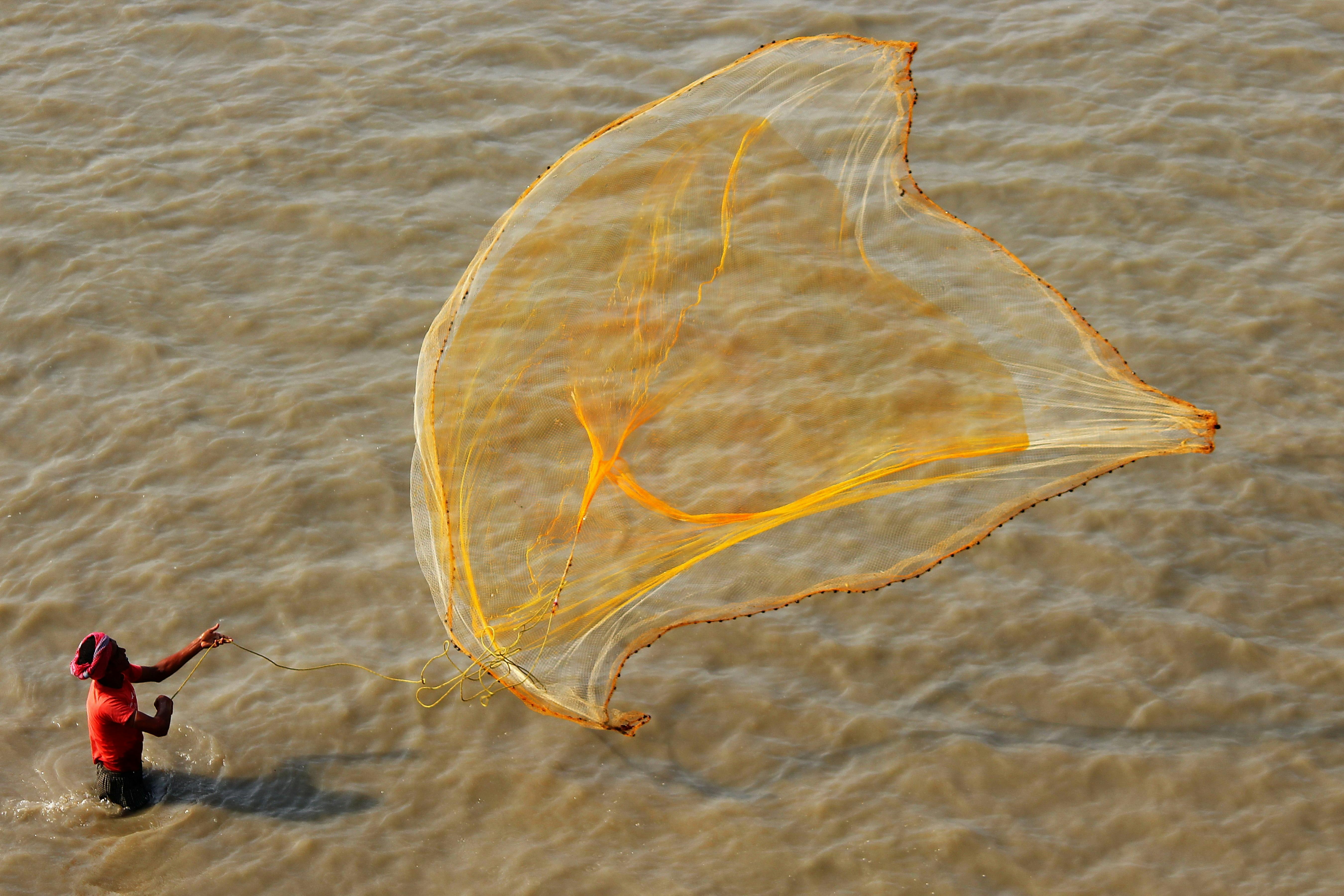 Topless Man Throwing Yellow Fish Net on Body of Water · Free Stock Photo