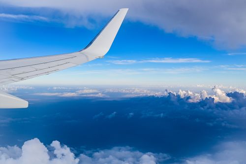 Free View of an airplane wing soaring above a beautiful cloudscape with blue sky. Stock Photo