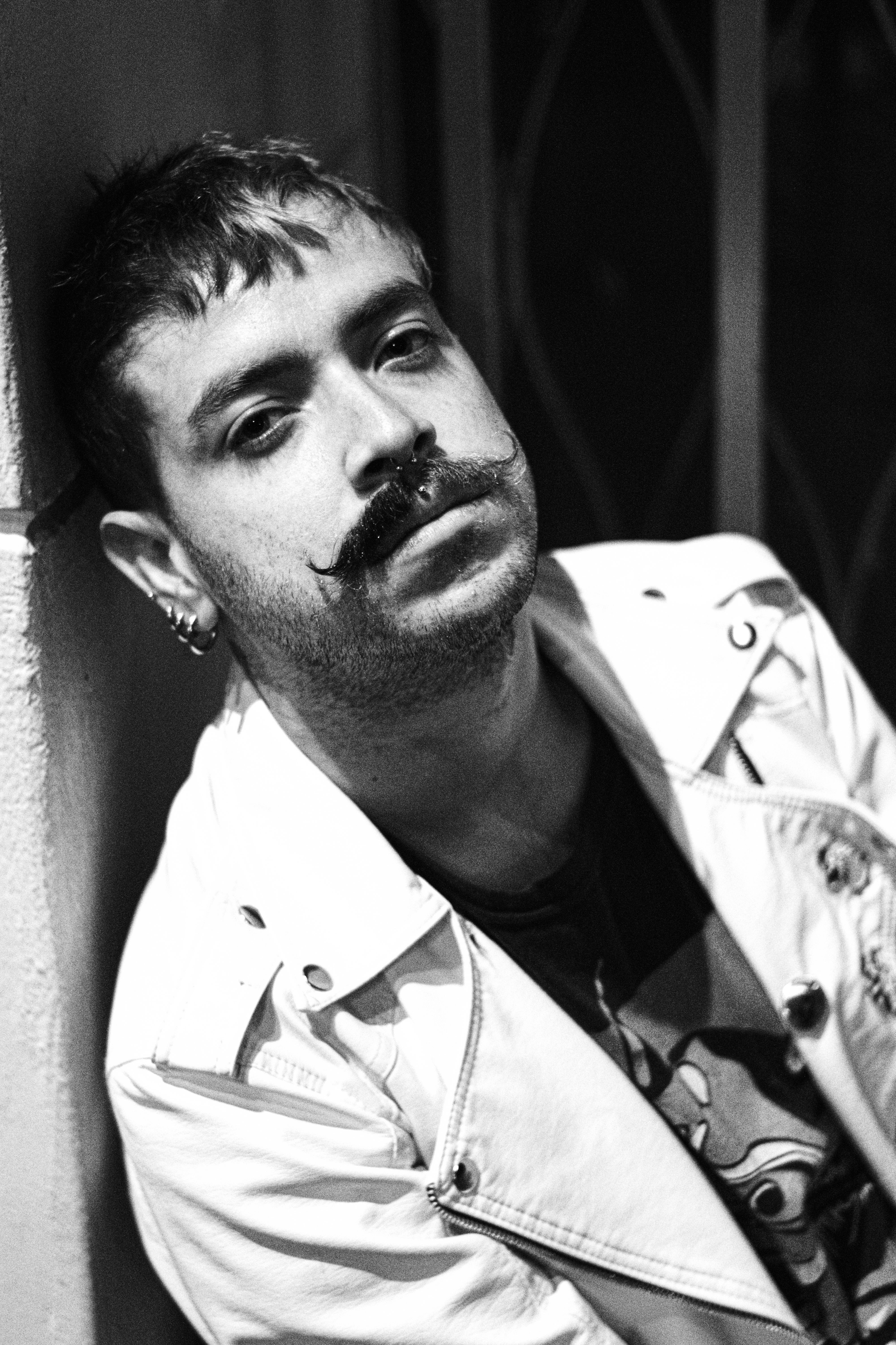 Grayscale portrait of a man with a distinctive mustache in a close-up shot.