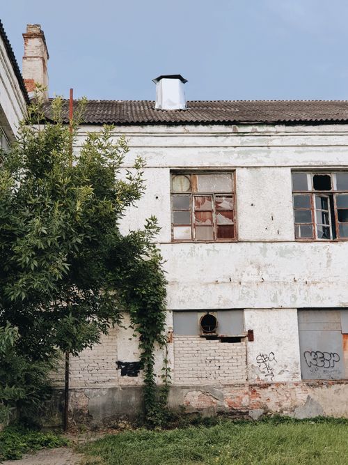Free Old, weathered building with cracked windows and ivy-covered walls, evoking a sense of neglect. Stock Photo