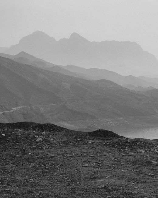Grayscale mountain range with clouds creating a dramatic view.