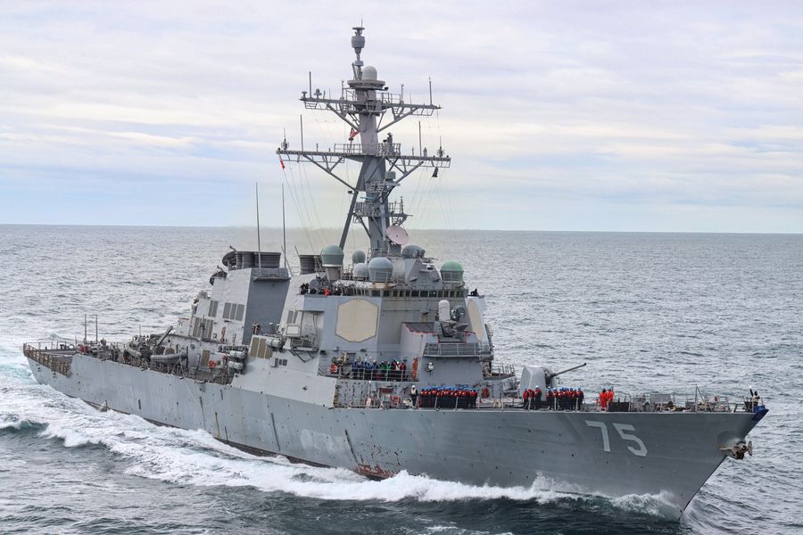 A United States Navy guided-missile destroyer under way in open water, crew lining the forward deck