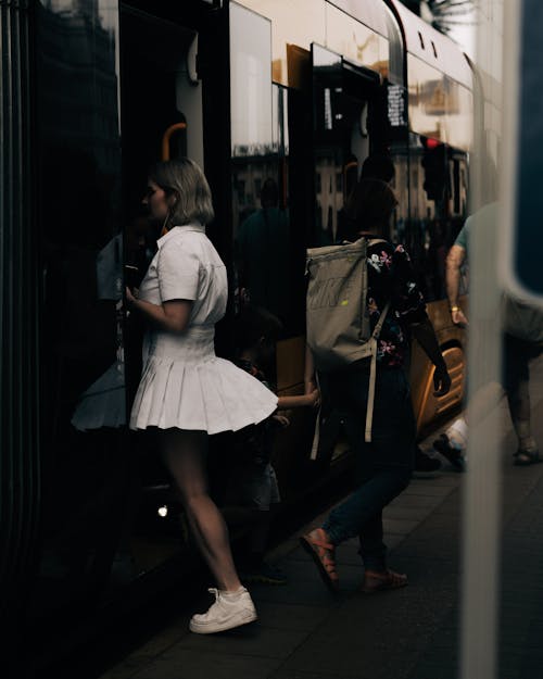Woman in White Top and Skirt Entering a Train