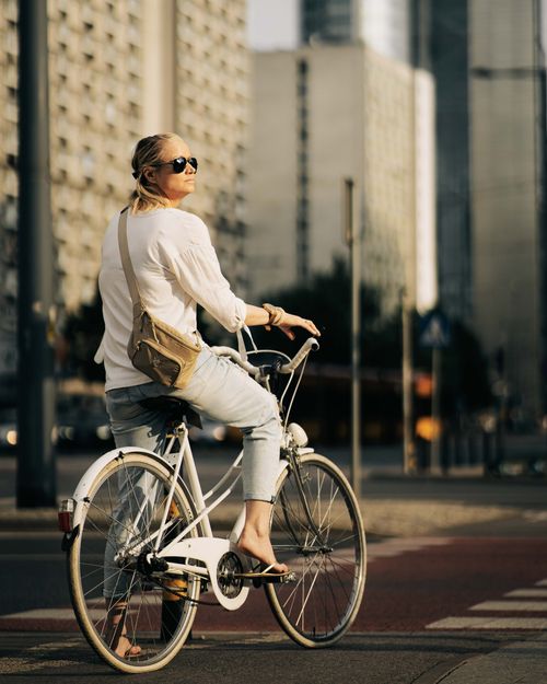 Free Woman riding a bicycle in a sunny urban setting, enjoying a summer afternoon. Stock Photo