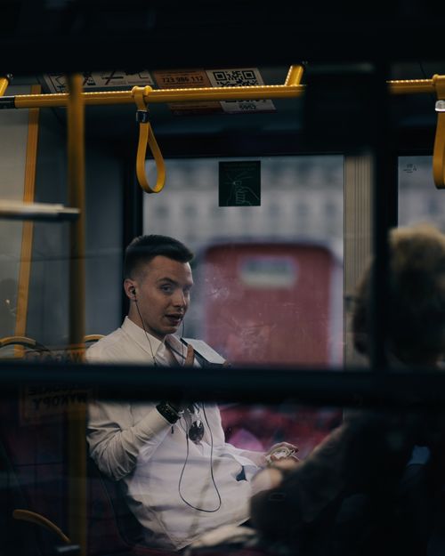 Free Man in white shirt with earphones on a tram, using a smartphone. Stock Photo