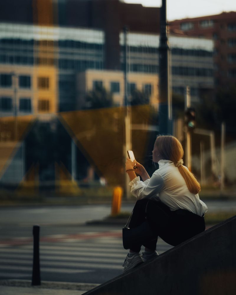 A woman sitting on steps using her phone in golden-hour light