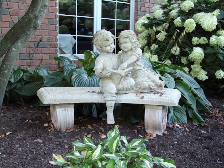 Stone Bench With Figures In Garden