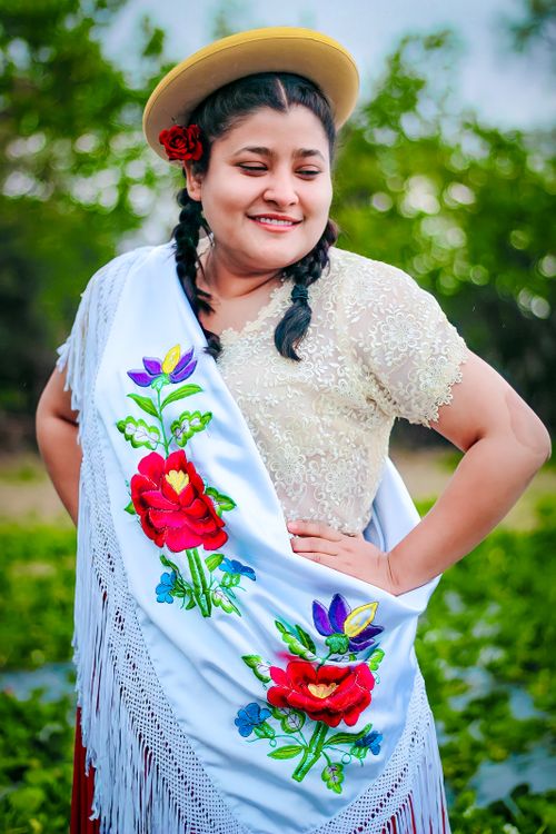 Free Smiling woman in traditional Bolivian attire with floral shawl and hat in nature setting. Stock Photo
