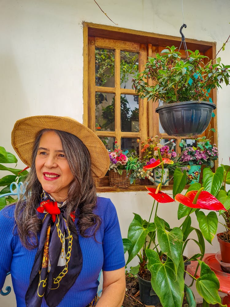 Elderly Woman In Hat Near House With Plants