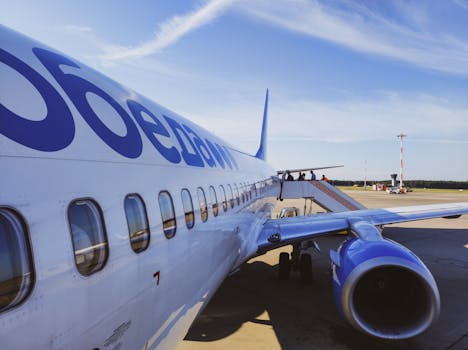 Side view of a commercial airplane with passengers boarding at a sunny airport.