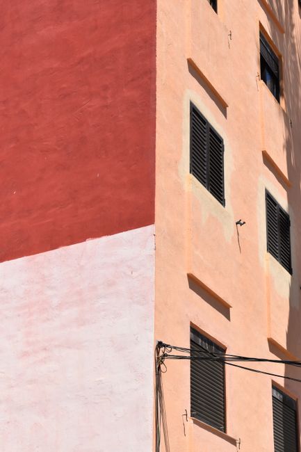 Brightly colored building exterior featuring black window shutters under daylight.