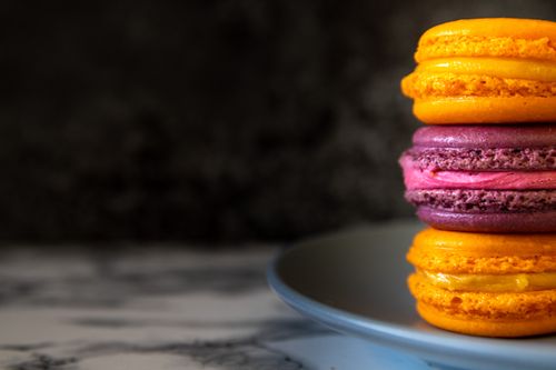 Free Close-up of colorful French macarons stacked on a plate, showcasing vibrant colors and textures. Stock Photo