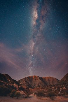A breathtaking view of the Milky Way shining brightly over the rugged mountains of La Rioja, Argentina.