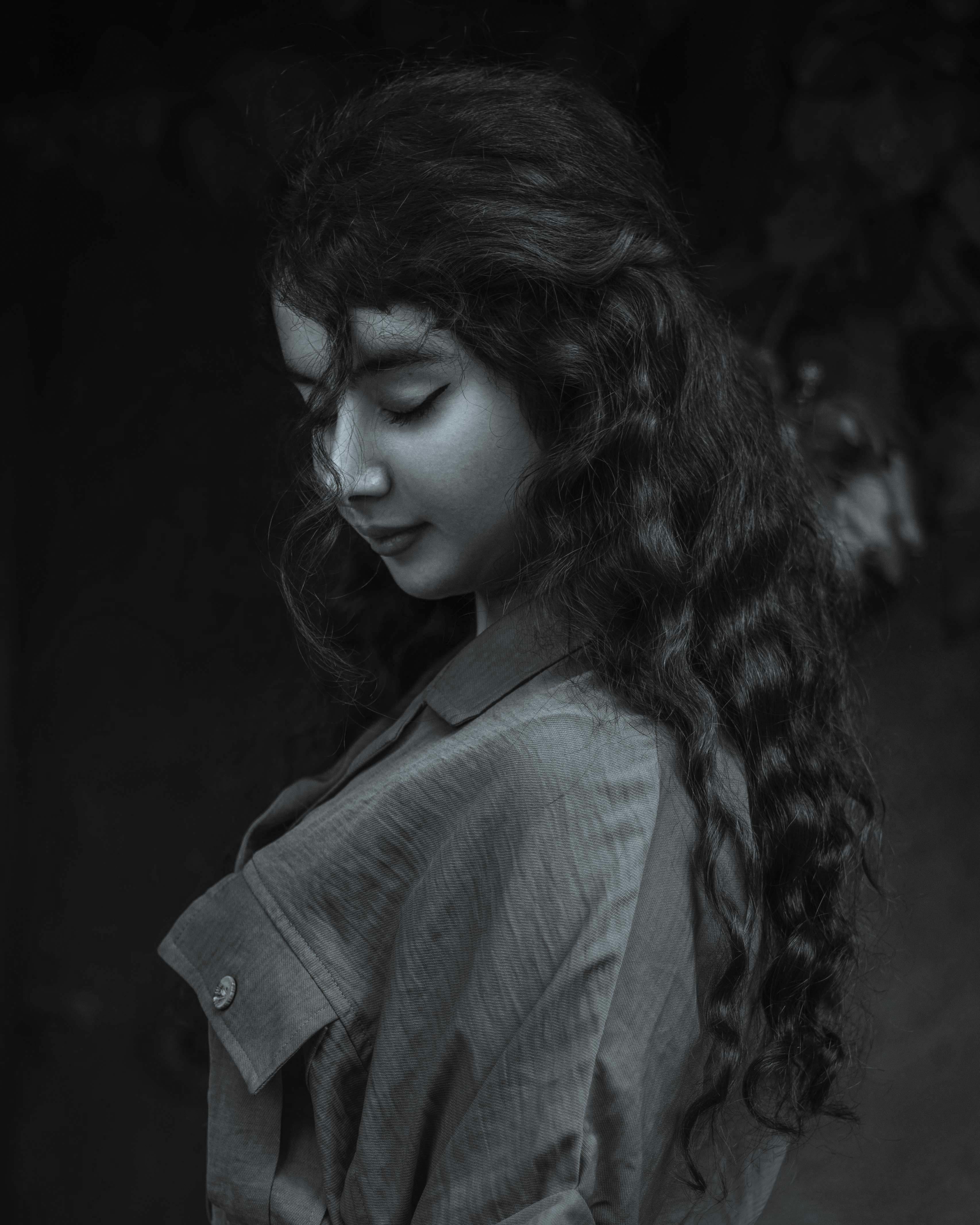 Captivating black-and-white photo of a woman with curly hair, exuding elegance and beauty.