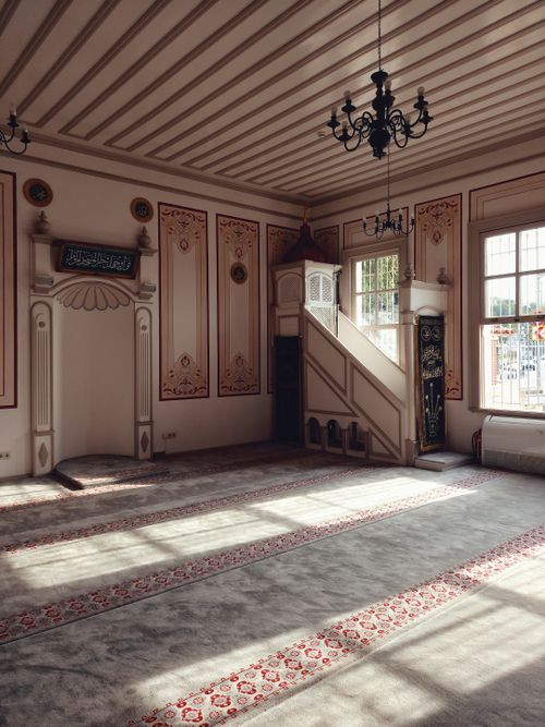 Free Sunlight streams through windows illuminating the ornate interior of a peaceful mosque prayer hall. Stock Photo
