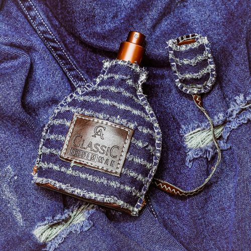 Free Close-up of a denim-wrapped perfume bottle on denim fabric showcasing unique style. Stock Photo