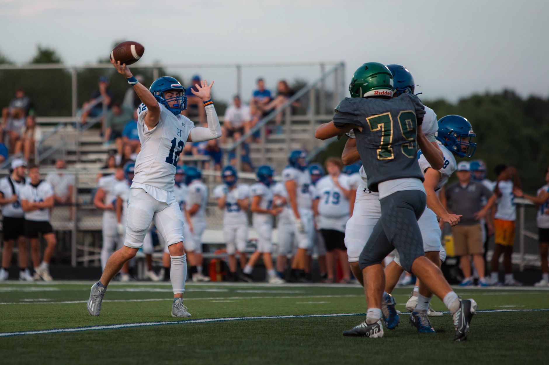 High school football game with quarterback throwing a pass under pressure.