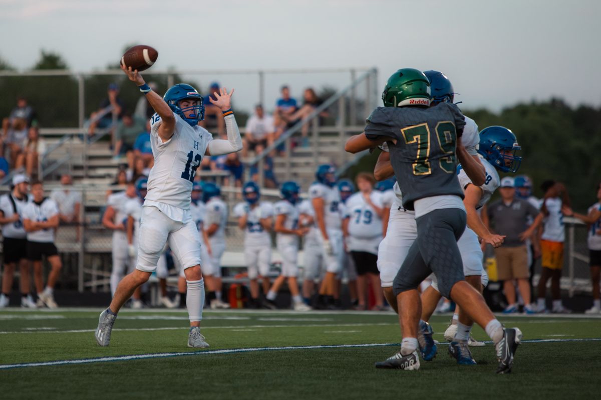 A quarterback in mid-throw during a competitive high school football game
