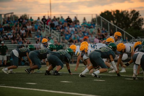 Free Teams face off in an intense high school football game as the sun sets, adding drama to the scene. Stock Photo