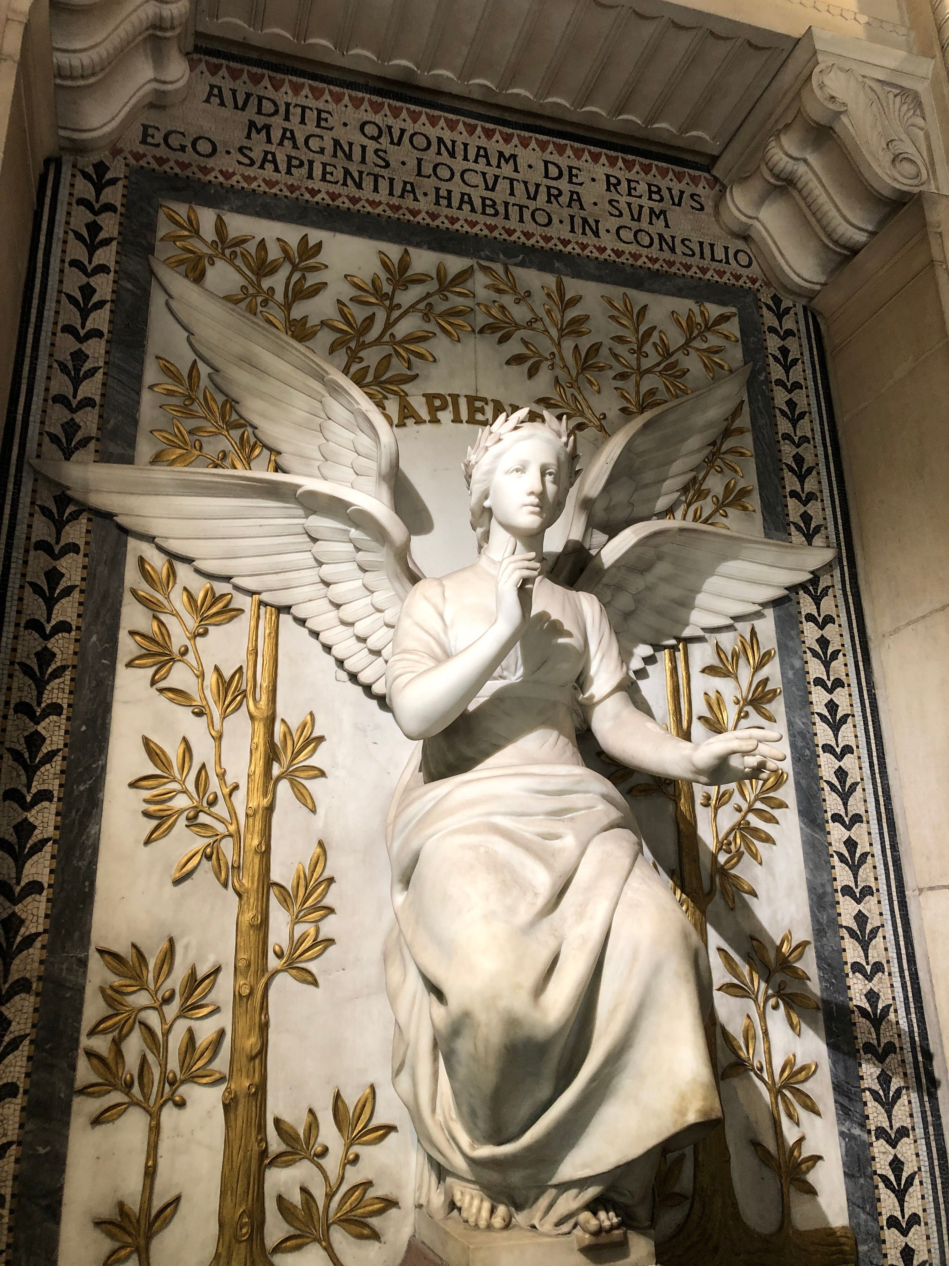 Intricate marble angel sculpture in Lyon, France, symbolizing wisdom and art.