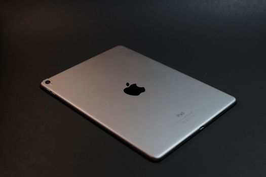 A modern silver tablet with a sleek design on a dark surface, showcasing advanced technology.