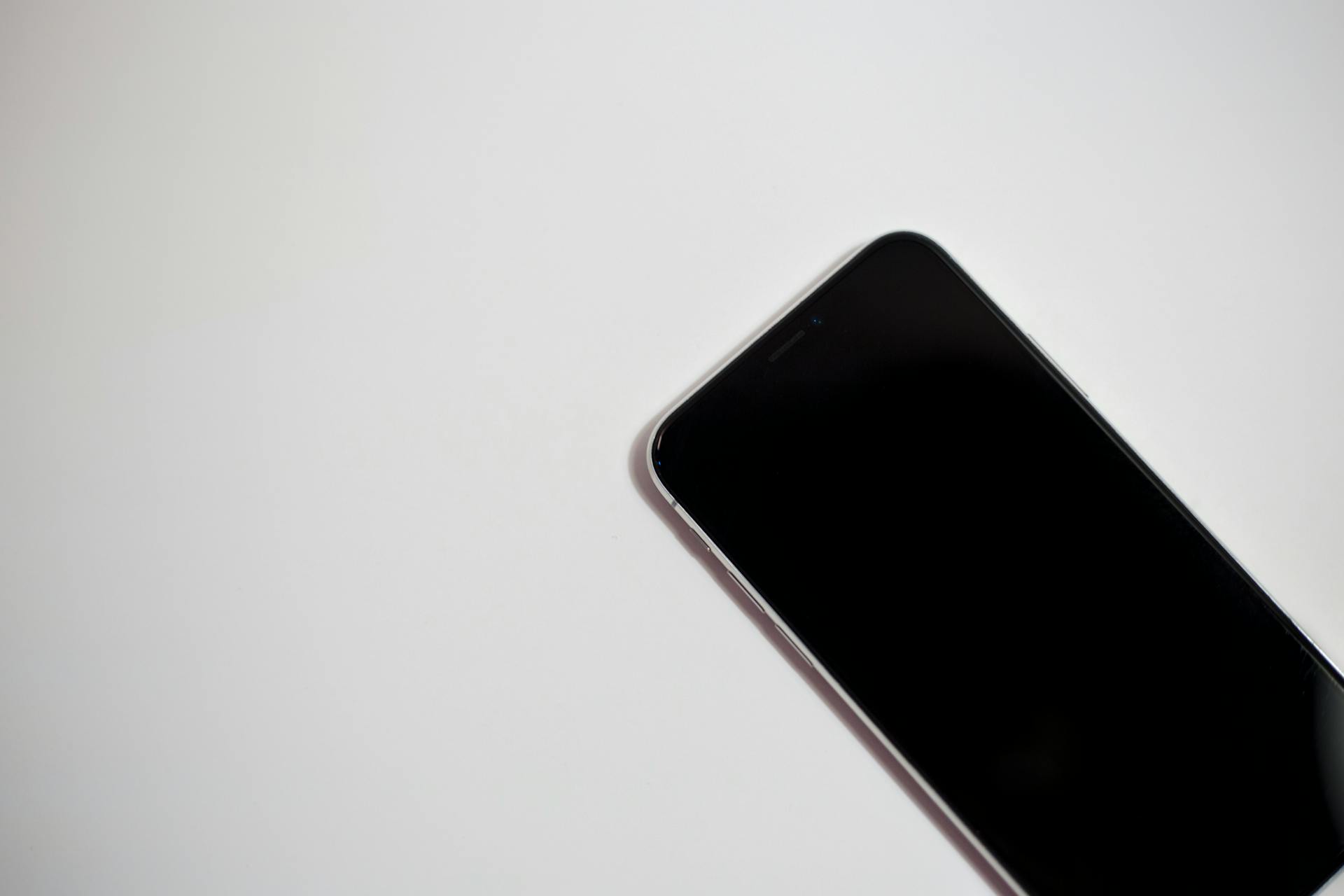 Close-up of a smartphone with black screen on a white background, perfect for technology themes.