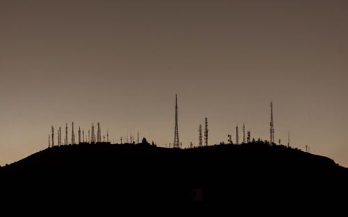 Free Silhouette of numerous communication towers on a hill during sunset. Stock Photo