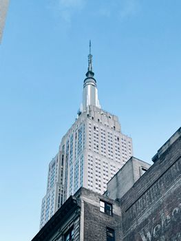 Low angle view of the iconic Empire State Building in New York City against a clear blue sky.
