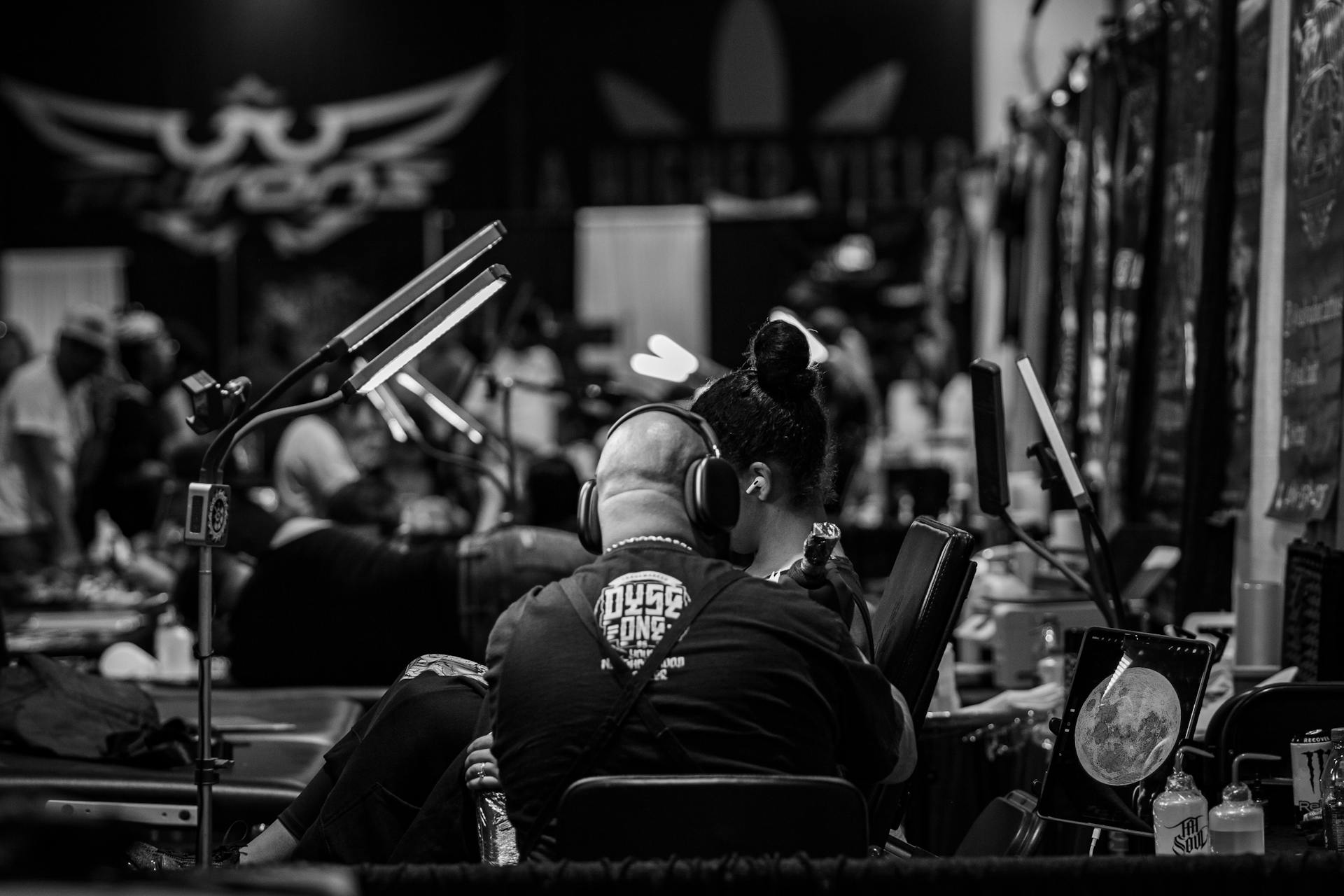 A tattoo artist working on a design in a busy parlor, Dallas, TX.