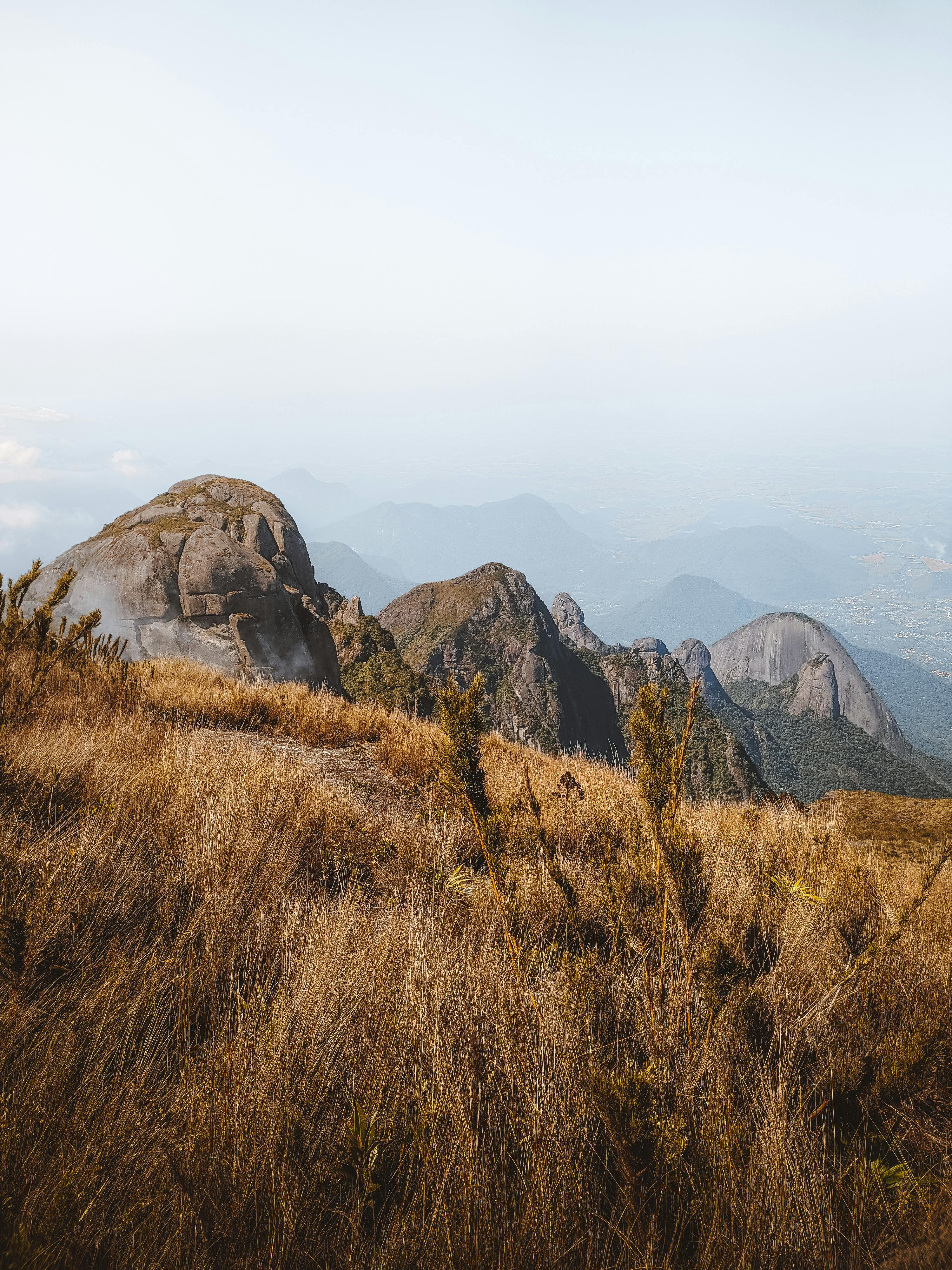 Brown grass and rocky mountains under a foggy sky. Ideal for nature photos.