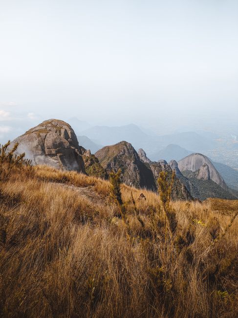 Brown grass and rocky mountains under a foggy sky. Ideal for nature photos.