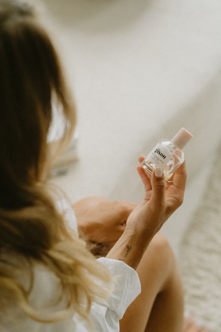 A woman holds a glass perfume bottle, emphasizing beauty and elegance.