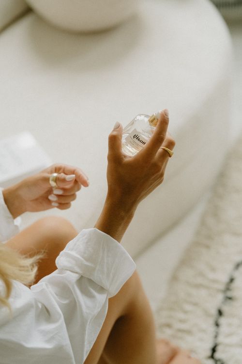 Free Close-up of a woman's hand holding a perfume bottle indoors, showcasing elegance and style. Stock Photo